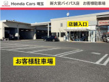当店のメインの入口側から見たお客様駐車場、及び店舗入口です。駐車場は広々としていますので、運転が苦手な方でも安心して駐車していただけます。ご来店時はスタッフがお出迎えに参ります。