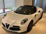 左斜め前から見た白い4Cスパイダー。曲面の多いフェンダーと低い室内が、コンパクトな車体の個性を伝えます。屋根を開けたブラウンの内装まで見渡せ、乗る前から気分が高まる姿です。