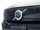 【ボルボの電気自動車を象徴するフロントフェイス】時代に合わせて変化するエンブレムデザイン。センターを斜めに大きく横切るラインと黒地に銀のアイアンマーク、これが最新ボルボのキャラクターアイコンです。