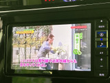 停車中にテレビ番組を視聴でき、待ち時間も車内で過ごしやすくなります。画面には番組映像と字幕が表示されており、車内でのひとときに映像を楽しめる便利な装備です。