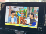 テレビ番組を画面で視聴でき、停車中の休憩時間にも映像を楽しめます。画面内には番組映像と字幕が表示されており、待ち時間を過ごす際の選択肢として活用いただけます。