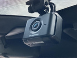 フロントガラス上部にカメラ型の機器が設置されています。運転中の状況を記録する用途で活用でき、万一の際の記録を残したい方にも心強い装備です。