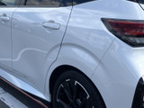 後席ドアからリアフェンダーへと続く曲線が、ボディに立体感を添えています。白い車体に同色のドアハンドルがなじみ、黒い足元と赤いサイドアクセントが引き締まった印象です。