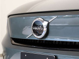 【ボルボの電気自動車を象徴するフロントフェイス】時代に合わせて変化するエンブレムデザイン。センターを斜めに大きく横切るラインと黒地に銀のアイアンマーク、これが最新ボルボのキャラクターアイコンです。