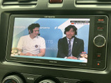 停車中にテレビ映像を視聴でき、待ち時間を過ごす際にも活用できます。画面に番組映像が表示され、車内で映像を楽しめる便利な装備です。ご利用の際は周囲の安全に配慮し、必ず停車した状態でお楽しみください。