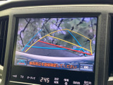 画面には車両後方の映像と進路の目安が表示され、駐車時の後方確認を助けます。画面内には周囲を直接確認するよう案内もあり、目視とあわせて車庫入れなどに活用できます。