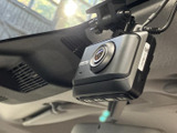 フロントガラス付近にカメラ型の機器が取り付けられており、運転席から手の届きやすい位置に配置されています。車内の視界を妨げにくい位置で、機器本体やボタンを確認できます。