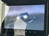 画面には道路を走る車両の映像が表示され、停車中の案内コンテンツとして楽しめます。時刻も確認でき、画面まわりのボタンから必要な操作へ移りやすい構成です。