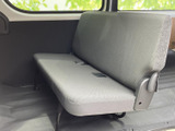 後席は横に広がるベンチシートで、複数人が並んで座れる室内空間です。窓から自然光が入り、グレーのシートと足元のフロアがすっきりとまとまった印象を与えています。