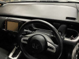 運転席まわりの写真です。ハンドルの左右にスイッチがあり、右奥にドリンクホルダーも見えます。