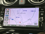 画面には周辺の地図が表示され、現在地や道路の位置関係を確認しやすい構成です。画面の両側に操作ボタンやつまみがまとまり、目的地設定や音声切替なども手元で扱いやすい配置です。