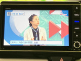画面にはテレビ番組が表示され、停車中に映像を楽しめます。周囲のボタンからメニューやオーディオ画面へ切り替えられる構成で、画面下部にはハザードスイッチも備わり、車内で扱いやすい配置です。
