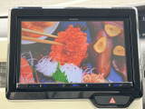 テレビ映像を表示できる画面を備えており、停車中の待ち時間などに映像を視聴できます。画面内に時刻も表示され、休憩中にも活用しやすい装備です。