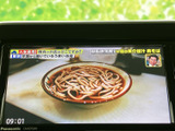 テレビ番組を表示できる画面を備え、停車中の待ち時間に映像を視聴できます。画面内に時刻も表示され、ひと目で確認しやすい実用的な装備です。